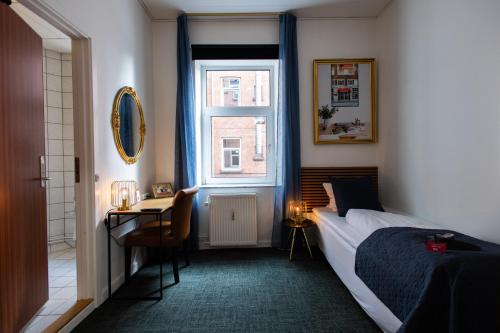a bedroom with a bed and a desk and a window at Milling Hotel Ansgar in Odense