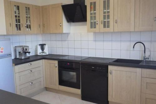 - une cuisine avec des placards en bois et un lave-vaisselle noir dans l'établissement Chez Dalmasso, à Arles