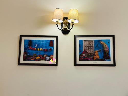 three framed pictures on a wall with a light at RAGHVENDRA HERITAGE in Jodhpur
