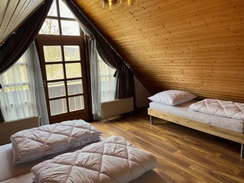 two beds in a room with wooden ceilings and windows at Ferienhaus 39 Kratzmühle Altmühlthal in Kinding