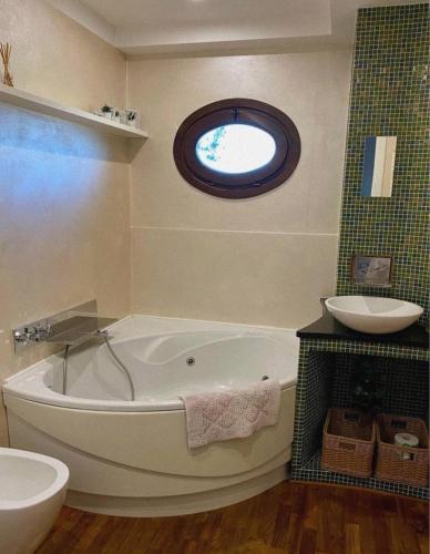 a bathroom with a tub and a sink and a window at Appartamento in Villa Aulla in Pontedera