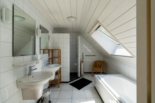een badkamer met 2 wastafels, een bad en een raam bij Wijndomein Erve Wisselink in Eibergen