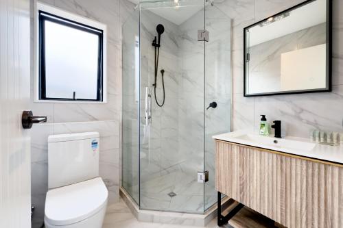 a bathroom with a shower and a toilet and a sink at Brand New 3-Bedroom Townhouse in Albany in Auckland