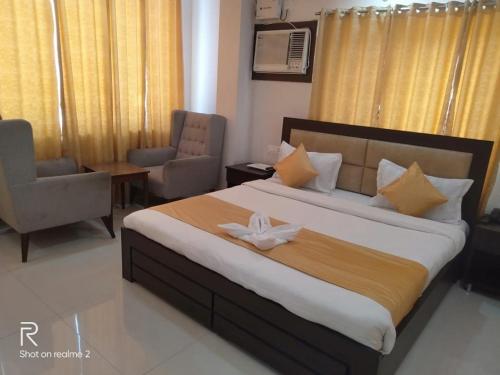 a bedroom with a large bed and a chair at Hotel Tulsi in Rishīkesh