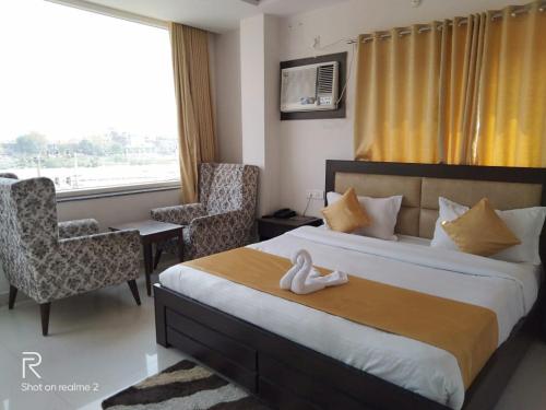 pokój hotelowy z łóżkiem, krzesłami i oknem w obiekcie Hotel Tulsi w mieście Rishikesh