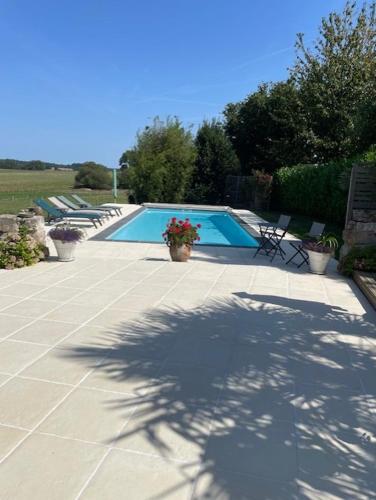 a swimming pool with chairs and a shadow on a patio at Lime Tree Farmhouse in Saint-Saud-Lacoussière