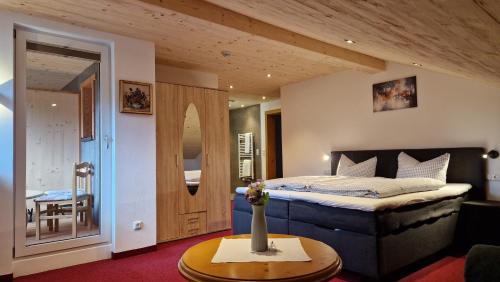 1 dormitorio con 1 cama con un jarrón sobre una mesa en Pension Bergheim, en Tannheim