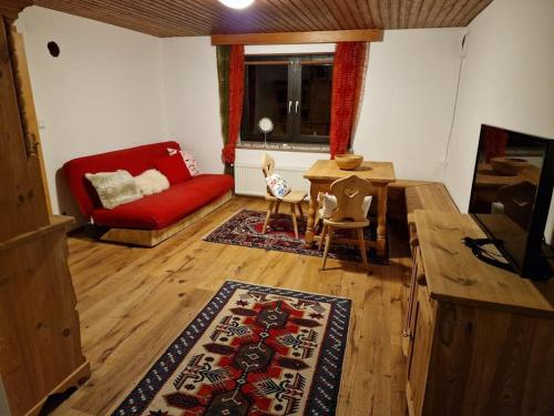 uma sala de estar com um sofá vermelho e uma mesa em Landhaus Tamberg im Schi-Weltcup-Ort Hinterstoder em Hinterstoder