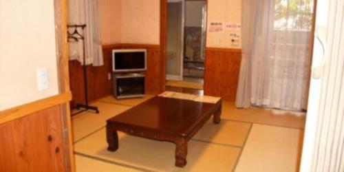 a living room with a coffee table and a tv at 水辺プラザかもと in Yamaga