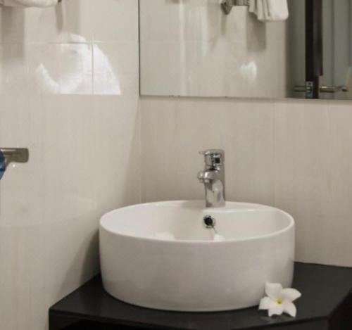 lavabo blanco en el baño con espejo en Guraidhoo Palm Inn, en Guraidhoo
