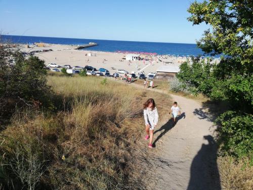 a woman and a child walking down a path at the beach at Emyra's holiday rooms in Constanţa