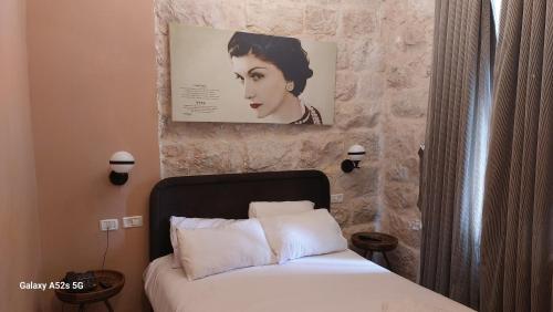a bedroom with a bed and a picture of a woman at malka house in El Muṣrāra