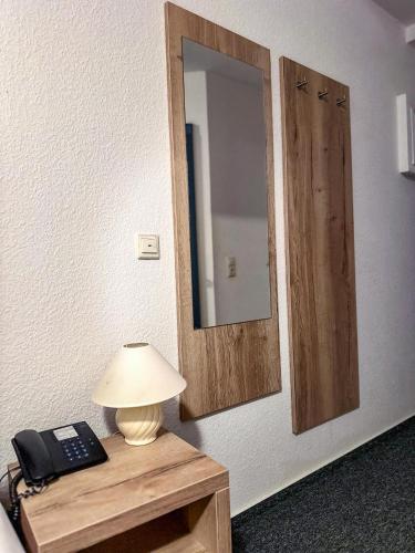 a lamp on a table with a mirror and a phone at Hotel & Restaurant Schaumburger Ritter, Rinteln in Rinteln