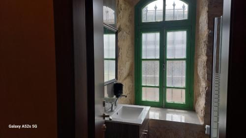 een badkamer met een groen raam en een wastafel bij malka house in El Muṣrāra