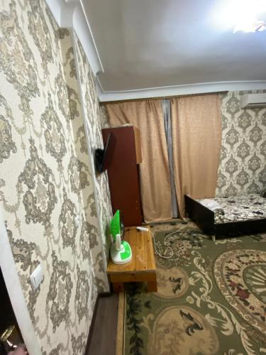 Una habitación con una cama y una mesa en una habitación en Исмаил Сомони 1, en Khujand
