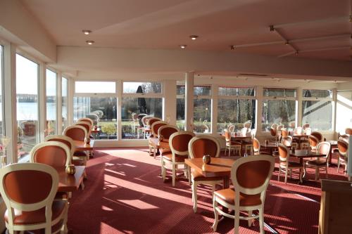 un comedor con mesas, sillas y ventanas en Milling Hotel Søpark, en Maribo