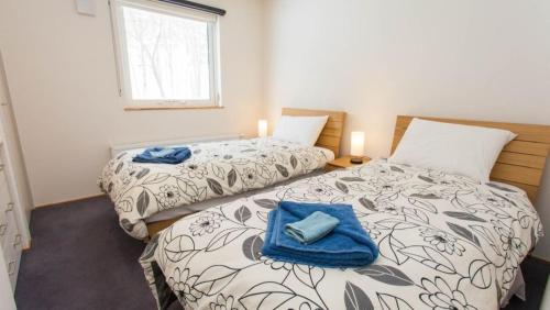 duas camas num quarto com duas toalhas azuis em Shirokin Chalet walking distance to Rusutsu Resort em Rusutsu