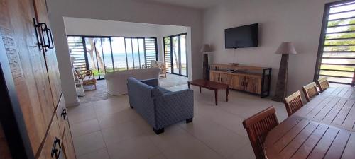 a living room with a television and a table and chairs at Canari Waterfront Villas in Roches Noires