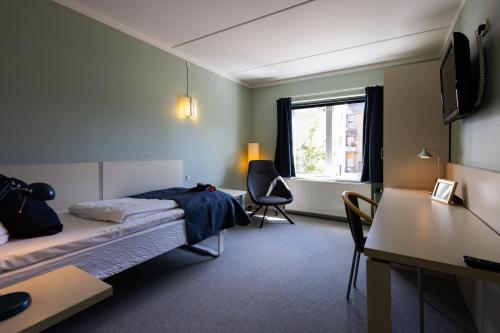 1 dormitorio con cama, escritorio y ventana en Milling Hotel Søpark, en Maribo