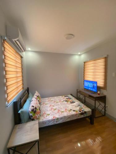a bedroom with a bed and a tv and two windows at Greenview Terraces in Kay Riapay