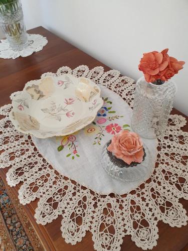 a table topped with a plate and a vase with flowers at la Bellavita rooms in Caltanissetta