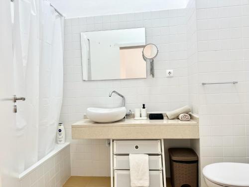 a white bathroom with a sink and a mirror at Maria da Vinha Porto Santo Beach House in Porto Santo