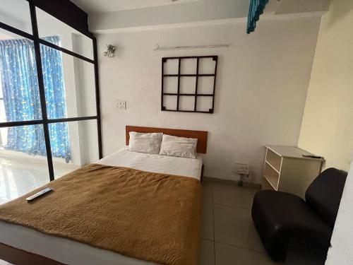 a bedroom with a bed with a chair and a window at Meera stays in Coimbatore