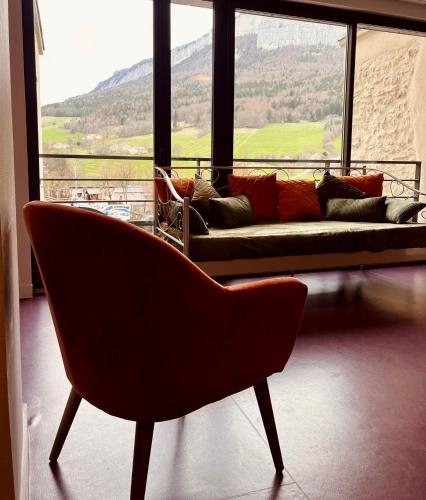 a living room with a couch in front of a window at Restaurant Hôtel du Vercors in Saint-Martin-en-Vercors