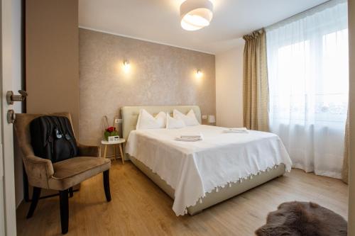 a bedroom with a bed and a chair and a window at Perfect Apartment Central in Braşov