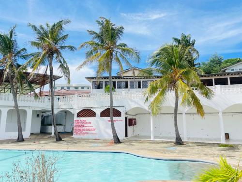 a building with palm trees and a swimming pool at Nyali Casa Beach Bliss in Mombasa