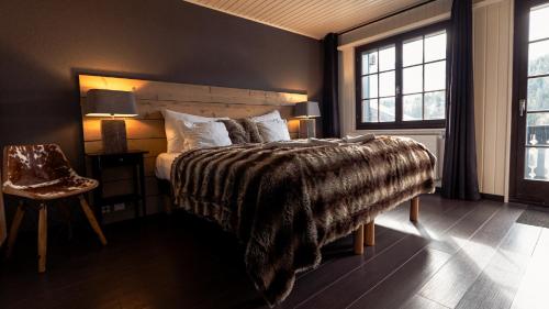 a bedroom with a bed with a blanket and two windows at Champoussin Lodge in Champoussin