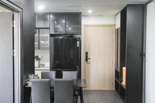 a kitchen with a table and a black refrigerator at Ly Homestay - Nera Garden Huế in Hue