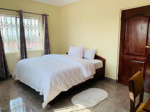 - une chambre avec un lit doté de draps blancs et une fenêtre dans l'établissement NIKOPS ROYAL HOTEL, à Accra