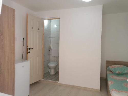 a white bathroom with a toilet and a door at Emyra's holiday rooms in Constanţa