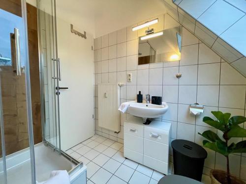 ein weißes Bad mit einem Waschbecken und einer Dusche in der Unterkunft Apartment Zschachwitz - frisch renovierter Wohlfühlort! in Dresden