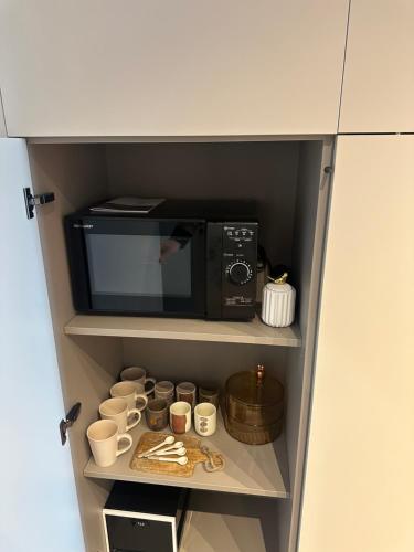 a cupboard with a microwave and some cups at Azuma Luxury Home in Bari