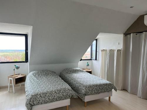 1 dormitorio con 2 camas y ventana en La maison du chêne, en Chaignay