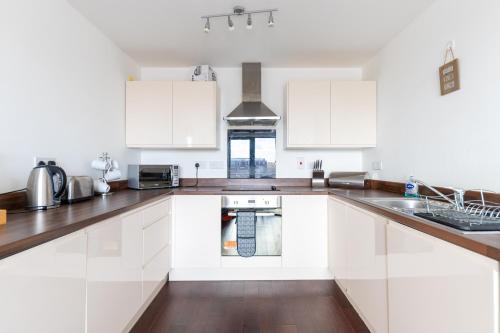 a kitchen with white cabinets and a sink at Stevenage - 2 Bedroom Apartment, Free Wifi & Balcony Upto 5 guests in Stevenage