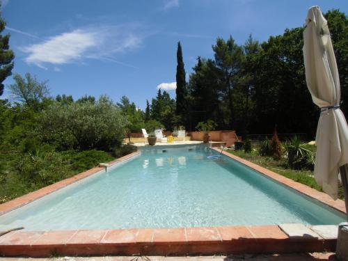 une piscine dans une cour avec un parasol dans l'établissement BASTIDE HOESPERELS, à Figanières