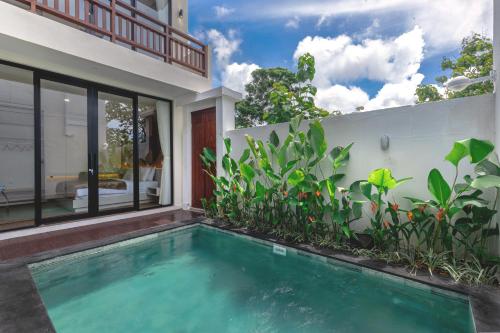 a swimming pool in front of a house with plants at Jobon Villas by Great Bali Villas in Uluwatu