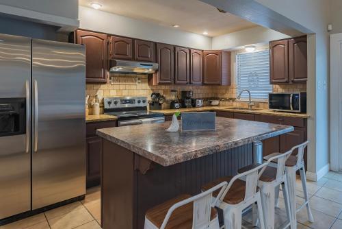 a kitchen with wooden cabinets and a stainless steel refrigerator at Pool, Gameroom & Minigolf Enchanting Texas Home in San Antonio