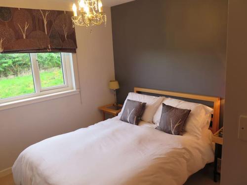 a bedroom with a white bed with pillows and a window at Stella Mara Cottage in Aultbea