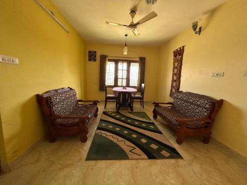 uma sala de estar com duas cadeiras e uma mesa em Madhu Manish Homestay and Rooms em Coonoor