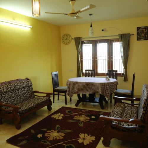 a living room with a table and chairs at Madhu Manish Homestay and Rooms in Coonoor
