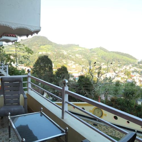 a balcony with a table and a chair and mountains at Madhu Manish Homestay and Rooms in Coonoor