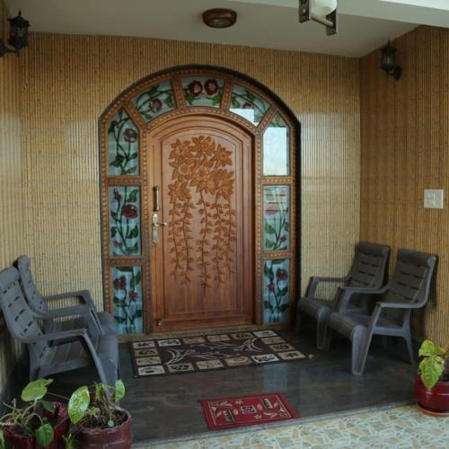 a wooden door with two chairs in a room at Madhu Manish Homestay and Rooms in Coonoor