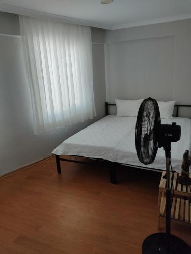 a room with a bed with a fan next to a window at Arya in Ayvalık