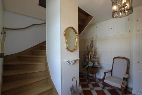 un couloir avec des escaliers, un miroir et une chaise dans l'établissement Domaine de Champouteau - Gîtes et Chambres d'hôtes, à Averdon