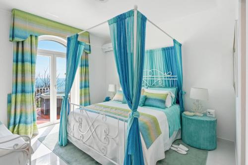 a bedroom with a canopy bed with blue curtains at Villa Navarra in Praiano