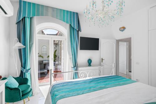 a bedroom with a bed with blue curtains and a chandelier at Villa Navarra in Praiano